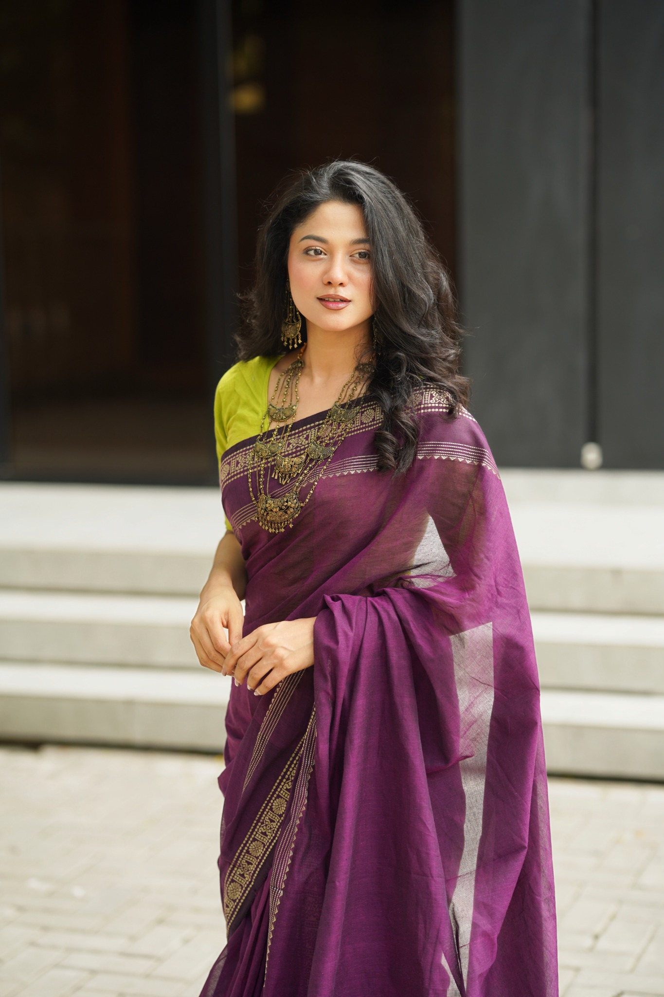দাঁড়িয়ে থাকা অবস্থায় বেগুনি শাড়ির ড্রেপ